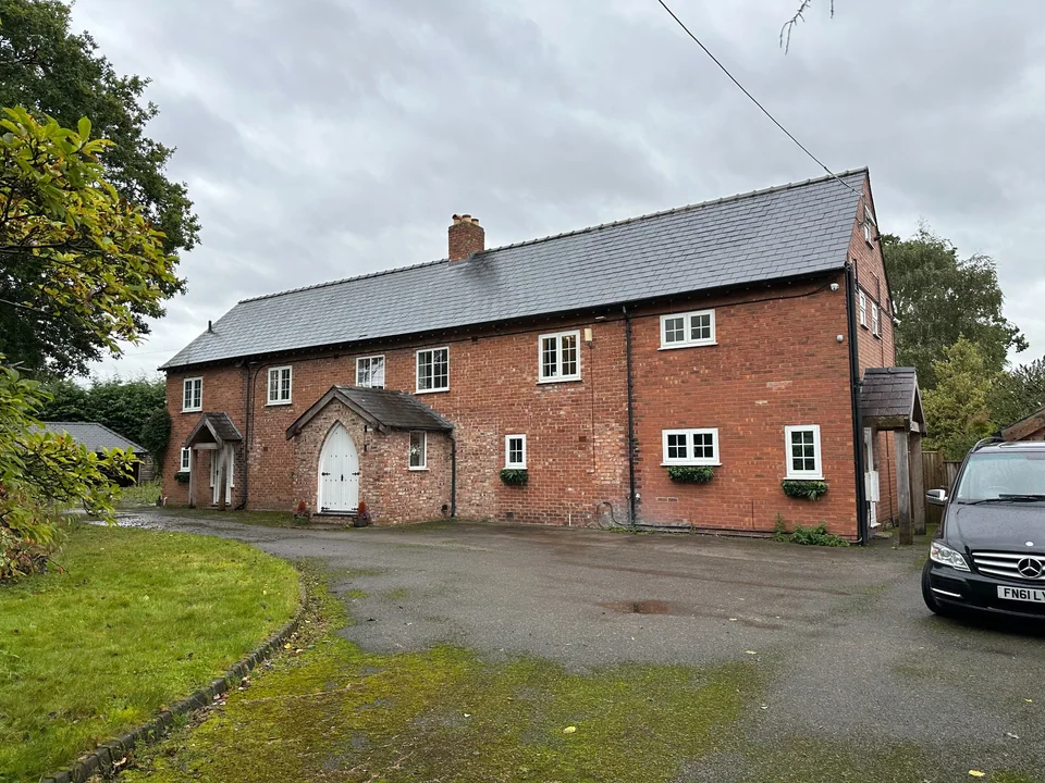 Long red-brick property with a slate roof, white windows and gabled entrance porches