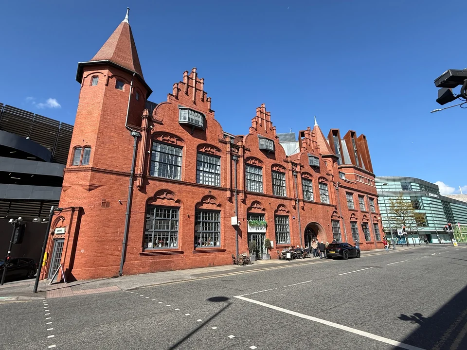 Ornate red-brick building with gables, a corner tower and tall windows