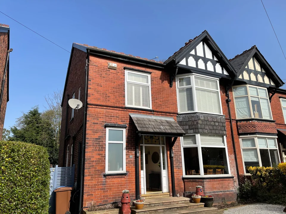 Red-brick semi-detached house with a decorative gable, bay windows and a slate entrance canopy