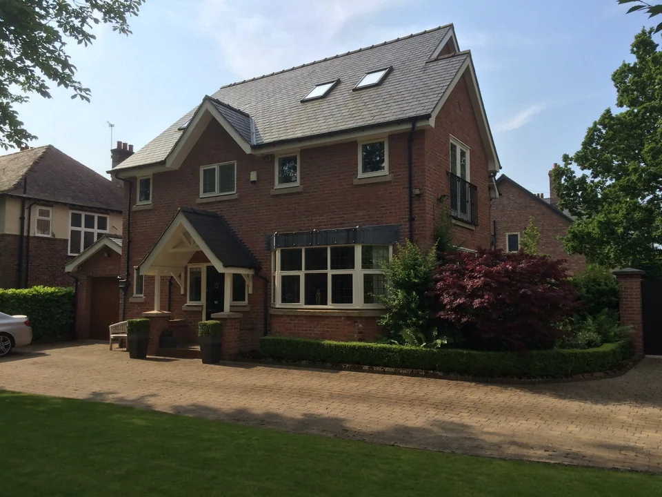 Detached red-brick house with a gabled pitched roof, rooflights and a timber entrance porch