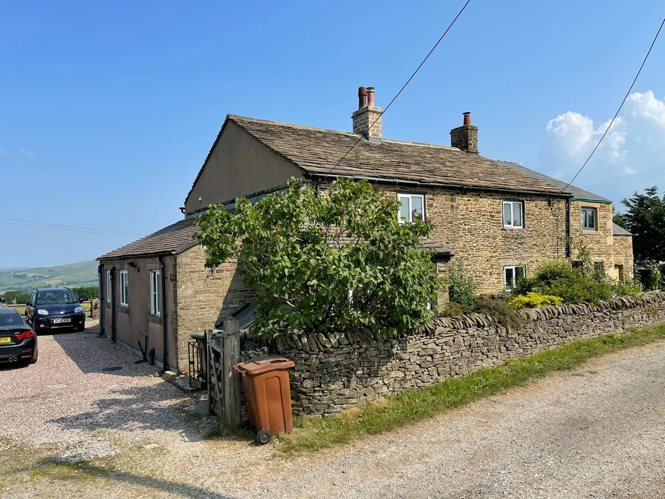 Traditional stone property with a stone boundary wall and countryside beyond