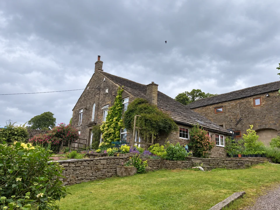 Traditional stone house with a pitched stone roof, chimney stacks and an established garden
