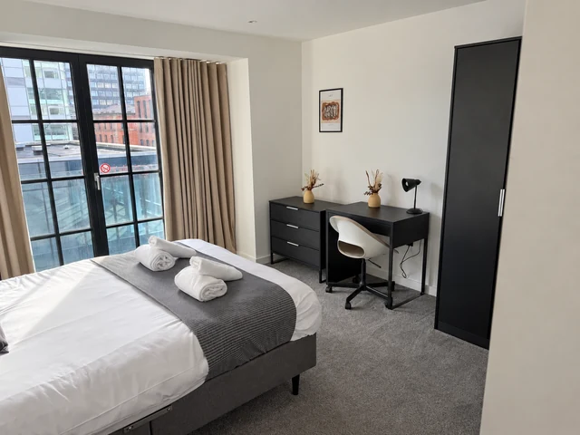 Bedroom with a double bed, desk, wardrobe and full-height glazing